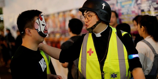 Pastor Alan Keung talks with a protester wearing a Halloween mask during an anti-government protest on Halloween in Hong Kong, China October 2019. (REUTERS/Kim Kyung-Hoon)