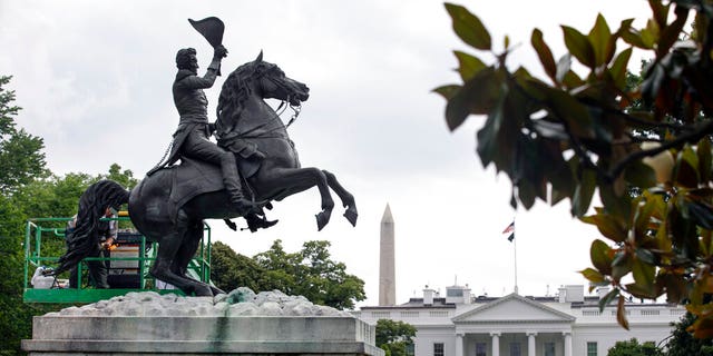 With the White House and the Washington Monument in the background, a National Park Service worker cleans a statue of President Andrew Jackson, Thursday, June 11, 2020, near the White House in Washington, after protests over the death of George Floyd, a black man who was in police custody in Minneapolis. Floyd died after being restrained by Minneapolis police officers. (AP Photo/Jacquelyn Martin)