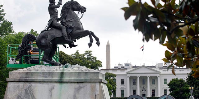 With the White House and the Washington Monument in the background, a National Park Service worker cleans a statue of President Andrew Jackson, Thursday, June 11, 2020, near the White House in Washington, after protests over the death of George Floyd, a black man who was in police custody in Minneapolis. Floyd died after being restrained by Minneapolis police officers. (AP Photo/Jacquelyn Martin)