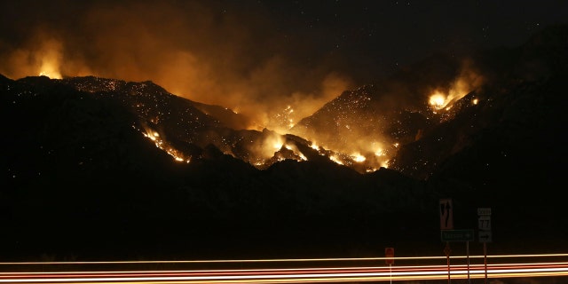Vehicle lights leave streaks a the Bighorn Fire moves along the western side of the Santa Catalina Mountains, June 14, in Oro Valley, Ariz.