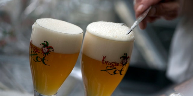 A worker scrapes the foam off of a glass of beer before serving in Bruges, Belgium. (AP)