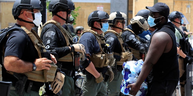 A demonstrator carrying water approaches as line of police as during a protest over the death of George Floyd, Wednesday, June 3, 2020, near the White House in Washington. Floyd died after being restrained by Minneapolis police officers. (AP Photo/Manuel Balce Ceneta)