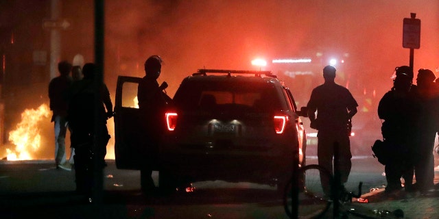 A police car burns, left rear, after being set on fire in Boston, Sunday, May 31, 2020.