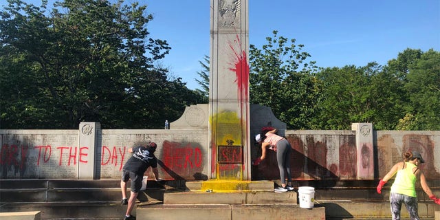 Local residents help clean up a World War II monument in Charlotte that had been defaced. 