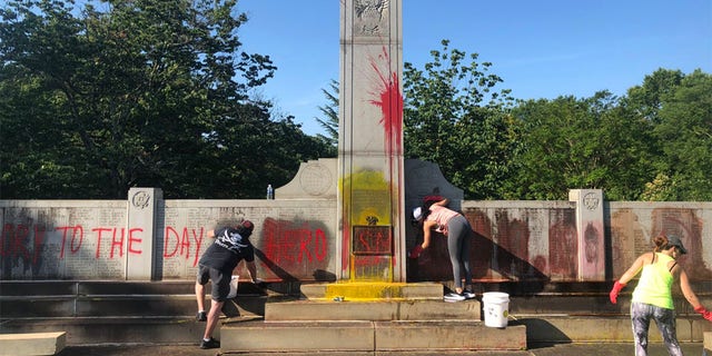 Local residents help clean up a World War II monument in Charlotte that had been defaced. 