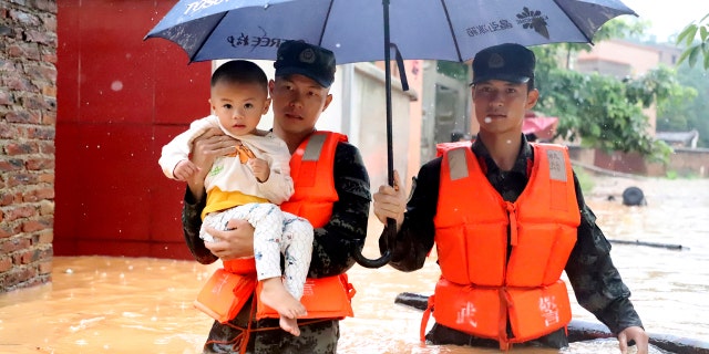 Rescuers carry a child to a boat during an evacuation of a flooded village in Qingyuan in southern China's Guangdong province on June 8.