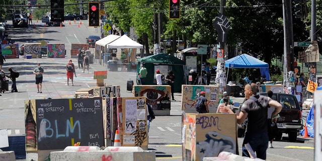 People walk amidst barricades in what has been named the Capitol Hill Occupied Protest zone in Seattle Monday, June 22, 2020. For the second time in less than 48 hours, there was a shooting near the 