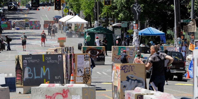 People walk amidst barricades in what has been named the Capitol Hill Occupied Protest zone in Seattle Monday, June 22, 2020. For the second time in less than 48 hours, there was a shooting near the