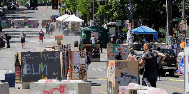 People walk amidst barricades in what has been named the Capitol Hill Occupied Protest zone in Seattle Monday, June 22, 2020. For the second time in less than 48 hours, there was a shooting near the 