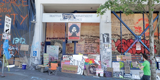 A person takes a photo of the Seattle Police East Precinct building, Monday, June 22, 2020, inside what has been named the Capitol Hill Occupied Protest zone in Seattle. (AP Photo/Ted S. Warren)