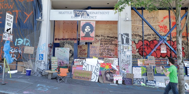 A person takes a photo of the Seattle Police East Precinct building, Monday, June 22, 2020, inside what has been named the Capitol Hill Occupied Protest zone in Seattle. (AP Photo/Ted S. Warren)