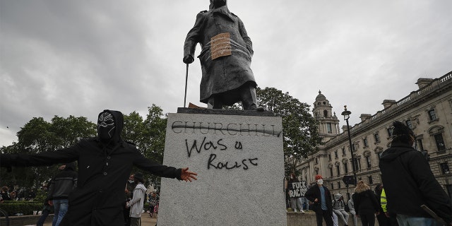 Protesters gather around a vandalized Winston Churchill statue in Parliament Square on Sunday. (AP)