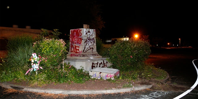 The defaced pedestal where a statue of Christopher Columbus once stood is seen at Byrd Park in Richmond, Va. Tuesday, June 9, 2020. The statue was torn down by protesters, set on fire and then thrown into a lake. News outlets report the figure was toppled less than two hours after protesters gathered in the city’s Byrd Park Tuesday chanting for the statue to be taken down. (Mark Gormus/Richmond Times-Dispatch via AP)