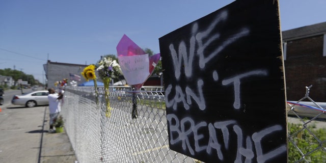 Dwayne Simmons makes a memorial to David McAtee near the intersection of 26th and Broadway, Tuesday, June 2, 2020, in Louisville, Ky. McAtee, the owner of a barbecue spot who was known for offering meals to police officers, died while police and National Guard soldiers were enforcing a curfew early Monday amid waves of protests over a previous police shooting. (AP Photo/Darron Cummings)