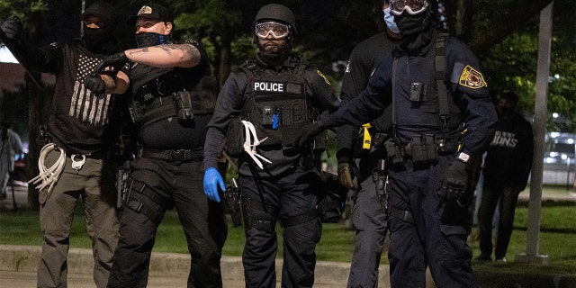 Detroit police officers point out protesters to arrest who were throwing rocks at the police after they dispersed the crowd, as protesters march through the streets of Detroit, Michigan for a second night May 30,2020, protesting the killing of George Floyd who was killed by a white officer who held his knee on his neck for several minutes during an arrest in Minneapolis on Monday. - Curfews were imposed on major US cities as clashes over police brutality erupted across America with demonstrators ignoring warnings from President Donald Trump that his government would stop the violent protests 