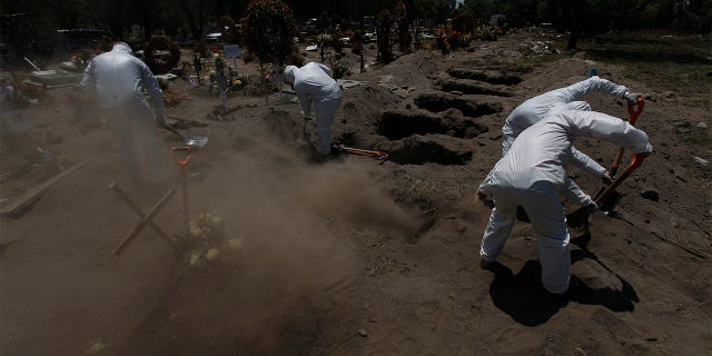 Cemetery workers in a protective gear shovel dirt over the gravesite of a COVID-19 victim at the Panteón de San Lorenzo Tezonco Iztapalapa cemetery, in a section for victims of the new coronavirus, in the Iztapalapa neighborhood of Mexico City, Tuesday, June 2, 2020. Mexico is passing through the pandemic’s most critical moment with a dramatically increasing number of confirmed and suspected infections. (AP Photo/Marco Ugarte)