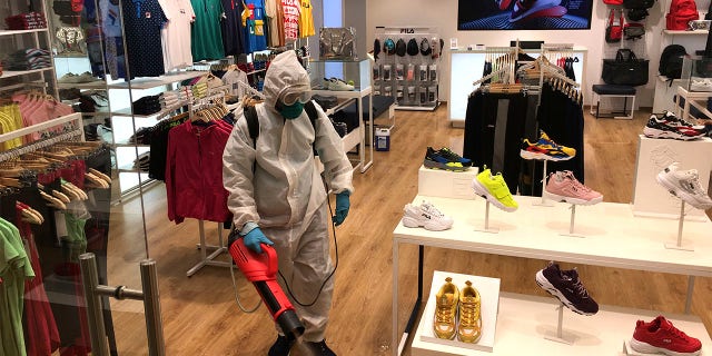 An employee of a shop disinfects the showroom at a mall that reopened in New Delhi, India, Monday, June 8, 2020. India is reopening its restaurants, shopping malls and religious places in most of its states after a more than 2-month-old lockdown even as the country continues to witness a worrying rise in new coronavirus infections. (AP Photo/Shonal Ganguly)