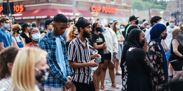 People listen at a service at the memorial location for George Floyd in Minneapolis, Minn.