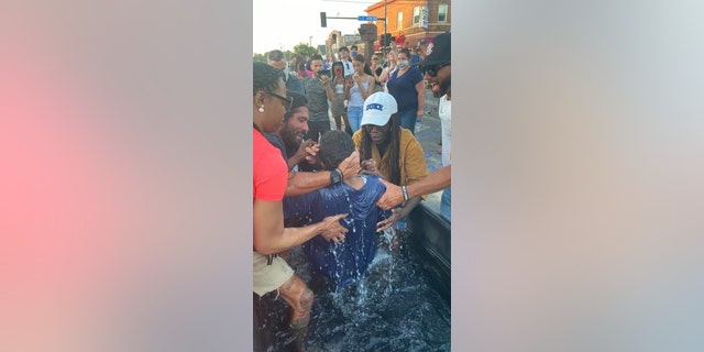 A person is baptized at the site where George Floyd was killed on Memorial Day at the hands of police officers. Several groups are holding daily services at that location offering hope and healing.