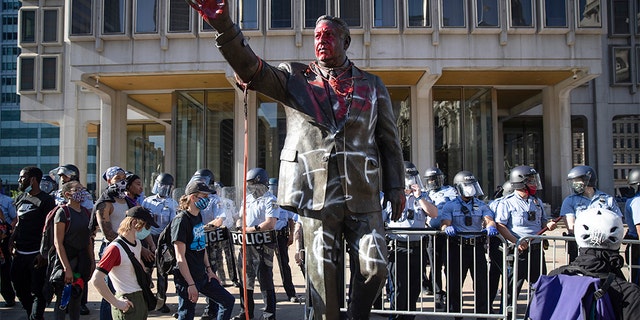 In this Saturday, May 30, 2020 photo police stand near a vandalized statue of controversial former Philadelphia Mayor Frank Rizzo in Philadelphia, during protests over the death of George Floyd, who died May 25 after he was restrained by Minneapolis police. Workers early Wednesday, June 3 removed the statue which was recently defaced during the weekend protest.