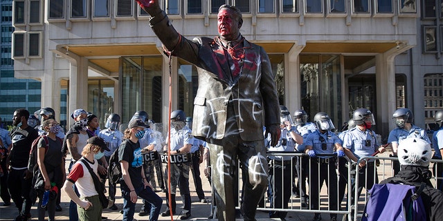 In this Saturday, May 30, 2020 photo police stand near a vandalized statue of controversial former Philadelphia Mayor Frank Rizzo in Philadelphia, during protests over the death of George Floyd, who died May 25 after he was restrained by Minneapolis police. Workers early Wednesday, June 3 removed the statue which was recently defaced during the weekend protest.