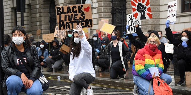 Demonstrators hold placards during a Black Lives Matter rally in Parliament Square in London, Saturday, June 6, 2020, as people protest against the killing of George Floyd by police officers in Minneapolis, USA. Floyd, a black man, died after he was restrained by Minneapolis police while in custody on May 25 in Minnesota. (AP Photo/Alberto Pezzali)