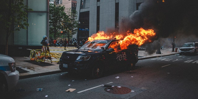 Protesters set fire to a police vehicle , on May 30, 2020 during a protest against the death of George Floyd, an unarmed black man who died while being arrested and pinned to the ground by the knee of a Minneapolis police officer.