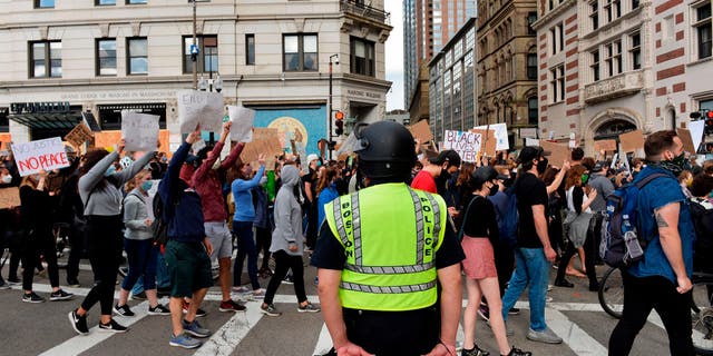A police officer holding a baton stands by as people march to call for Police Department reform as part of the "Unite Against Racist Police Terror! Boston Speakout and March" in Boston, Massachusetts on June 7, 2020. - Protesters have rallied for racial justice in cities across the United States following the death of George Floyd at the hands of police on May 25. (Photo by Joseph Prezioso / AFP) (Photo by JOSEPH PREZIOSO/AFP via Getty Images)