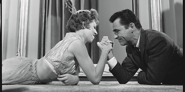 In an off-camera moment, Rod Serling arm wrestles with Carol Burnett.