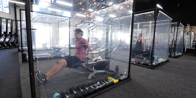 People exercise at Inspire South Bay Fitness behind plastic sheets in their workout pods while observing social distancing on June 15.