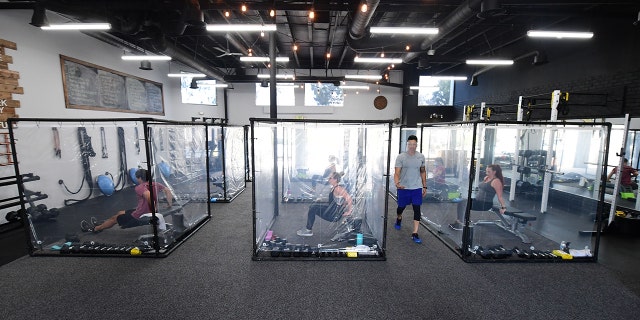Peet Sapsin leads a class at Inspire South Bay Fitness with students behind plastic sheets in their workout pods on June 15.