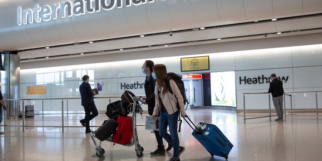 A pair of passengers wearing face masks are seen preparing for airline travel amid the coronavirus. (AP Photo/Matt Dunham)