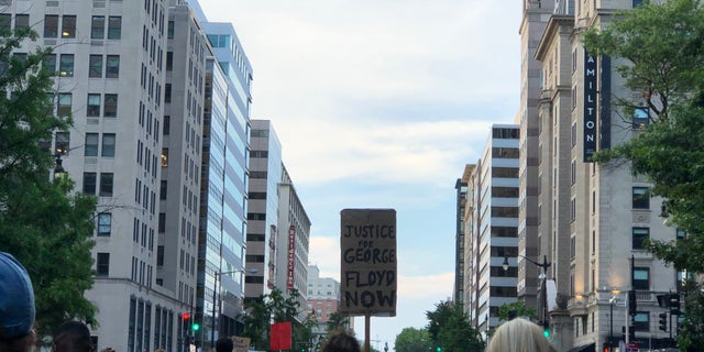 Demonstrators carry signs reading, for example, "Justice for George Floyd Now."