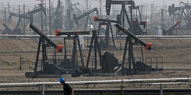 A worker walks past pump jacks operating at the Kern River Oil Field in Bakersfield, California.