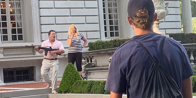 A couple draws their firearms on protestors as they enter their neighborhood during a protest against St. Louis Mayor Lyda Krewson, in St. Louis, Missouri, U.S. June 28, 2020, in this picture grab obtained from a social media video. (DANIEL SHULAR/via REUTERS. THIS IMAGE HAS BEEN SUPPLIED BY A THIRD PARTY.)