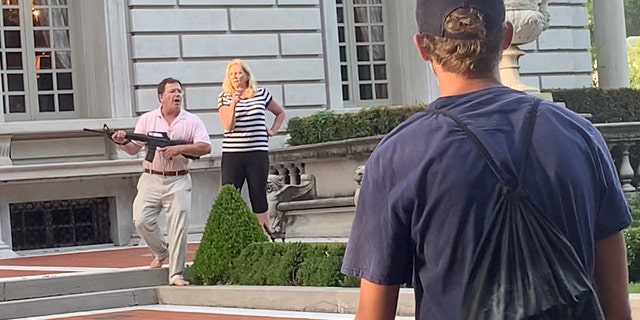 A couple draws their firearms on protestors as they enter their neighborhood during a protest against St. Louis Mayor Lyda Krewson, in St. Louis, Missouri, U.S. June 28, 2020, in this picture grab obtained from a social media video. (DANIEL SHULAR/via REUTERS. THIS IMAGE HAS BEEN SUPPLIED BY A THIRD PARTY.)