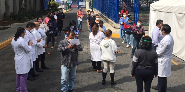 Juarez public hospital health workers wait on a street after a 7.4 earthquake sent them out from their work areas, in Mexico City, Tuesday, June 23, 2020.
