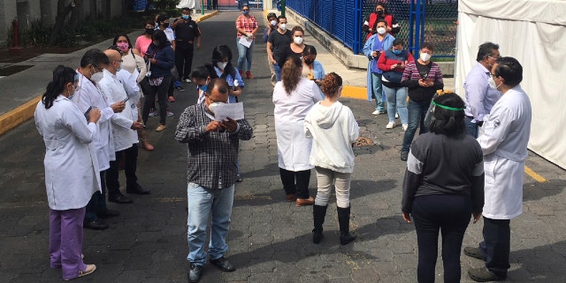 Juarez public hospital health workers wait on a street after a 7.4 earthquake sent them out from their work areas, in Mexico City, Tuesday, June 23, 2020.