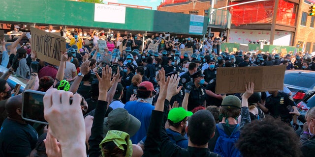 A large group of protesters surround members of the New York City Police Department in the Brooklyn borough of New York on Saturday. (AP)