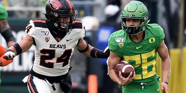 Running back Travis Dye #26 of the Oregon Ducks runs with the ball as defensive back David Morris #24 and defensive back Jaydon Grant #3 of the Oregon State Beavers give chase during the first half of the game at Autzen Stadium on November 30, 2019 in Eugene, Oregon. (Photo by Steve Dykes/Getty Images)