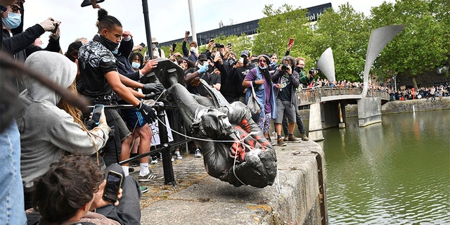 Protesters throw a statue of slave trader Edward Colston into Bristol harbor, during a Black Lives Matter protest rally in Bristol, England on Sunday. (AP/PA)