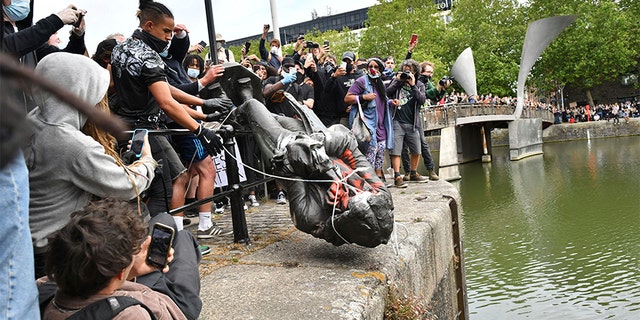 Protesters throw a statue of slave trader Edward Colston into Bristol harbor, during a Black Lives Matter protest rally in Bristol, England on Sunday. (AP/PA)