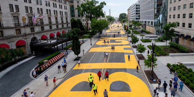 The Washington Monument and the White House are visible behind the words Black Lives Matter sign that has been painted in bright yellow letters on the 16th Street by city workers and activists, Friday, June 5, 2020, in Washington. (Khalid Naji-Allah/Executive Office of the Mayor via AP)