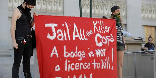 People hold up a sign in Oakland, Calif., Thursday, June 4, 2020, at a protest over the death of George Floyd, who died May 25 after being restrained by police in Minneapolis. (AP Photo/Ben Margot)