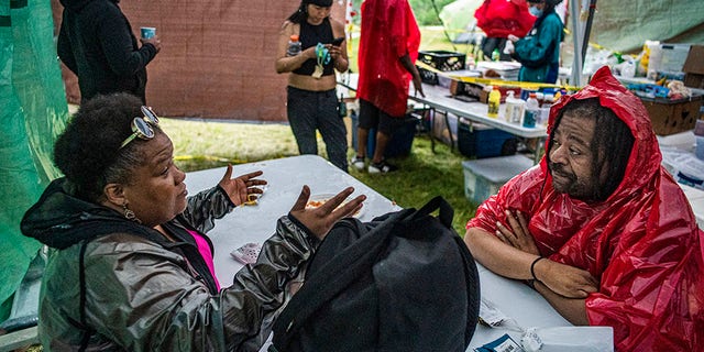 Park & Recreation Board Commissioner Londel French, right, who has been spending a lot of time at Powderhorn Park making sure that the encampment is a safe environment for the homeless, chats with formerly homeless advocate Tyra Thomas on Thursday, June 18, 2020, in Minneapolis. (Richard Tsong-Taatarii/Star Tribune via AP)