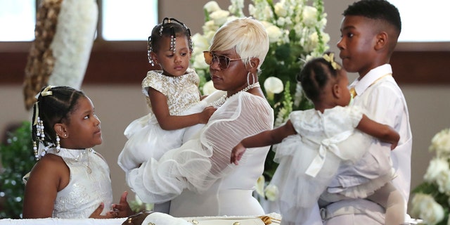 Tomika Miller, the wife of Rayshard Brooks, holding their 2-year-old daughter, Memory, while pausing with her children during the family processional at his funeral in Ebenezer Baptist Church on Tuesday in Atlanta. (Curtis Compton/Atlanta Journal-Constitution via AP, Pool)