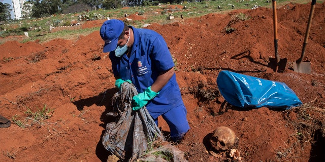 A cemetery worker exhumes the body of a person buried three years ago at the Vila Formosa cemetery, which does not charge families for the gravesites, in Sao Paulo, Brazil, Friday, June 12, 2020. Three years after burials, remains are routinely exhumated and stored in plastic bags to make room for more burials, which have increased amid the new coronavirus. (AP Photo/Andre Penner)