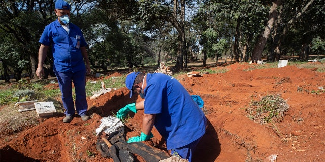Cemetery workers exhume a body that was buried three years ago at the Vila Formosa cemetery, which does not charge families for the gravesites, in Sao Paulo, Brazil, Friday, June 12, 2020. Three years after burials, remains are routinely exhumated and stored in plastic bags to make room for more burials, which have increased amid the new coronavirus. (AP Photo/Andre Penner)