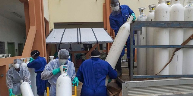 Medical workers offload cylinders of oxygen at the Donka public hospital where coronavirus patients are treated in Conakry, Guinea, on Wednesday, May 20, 2020. Before the coronavirus crisis, the hospital in the capital was going through 20 oxygen cylinders a day. By May, the hospital was at 40 a day and rising, according to Dr. Billy Sivahera of the aid group Alliance for International Medical Action. Oxygen is the the facility's fastest-growing expense, and the daily deliveries of cylinders are taking their toll on budgets. (AP Photo/Youssouf Bah)