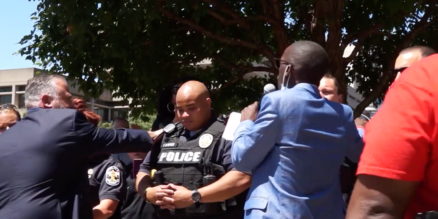 Pastor Brian Gibson prays over police officers with other faith leaders during a rally Tuesday in Louisville, Ky.